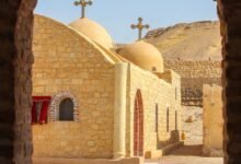 دير الملاك غبريال بجبل النقلون شاهد التاريخ والفن القبطي منذ القرن الثالث الميلادي يقع دير الملاك غبريال في جبل النقلون على بعد 16 كم جنوب شرق مدينة الفيوم بمركز إطسا، ويعود تاريخ تأسيسه إلى القرن الثالث الميلادي، ويعد من أقدم وأهم الأديرة في مصر التي تحافظ على إرث الرهبنة والفن القبطي. تاريخ دير الملاك غبريال بدأت الرهبنة في دير الملاك غبريال في القرن الرابع الميلادي، وقد زار الأنبا أنطونيوس هذا الدير مرتين، الأولى في عام 285 ميلادي، والثانية خلال القرن الرابع الميلادي، وهو ما يعكس أهمية الدير كمركز روحي وتعليمي للرهبان منذ العصور الأولى. يطلق على الدير أيضًا اسم دير أبي خشبة، وقصة هذه التسمية محفوظة في مخطوط قديم موجود في المتحف القبطي بمنطقة مصر القديمة، وتقول القصة إن هناك خشبة في سقف الكنيسة تُشير إلى فيضان نهر النيل. خلال وقت القداس، إذا هبط من هذه الخشبة ماء كثير فهذا يشير إلى أن السنة ستشهد رخاء، أما إذا ظهر الماء بشكل بسيط يشبه العرق، فهذا كان يُشير إلى حدوث جوع. يضم الدير كنيستين أساسيتين، هما كنيسة الملاك غبريال وكنيسة القديس مارجرجس، وتزين جدران كل كنيسة رسومات وأشكال فنية غير عادية للفن القبطي في العصور الوسطى، وقد نُفذت هذه الرسومات بمهارة فائقة، ما يجعل الدير شاهدًا حيًا على تاريخ الفن والدين في مصر.